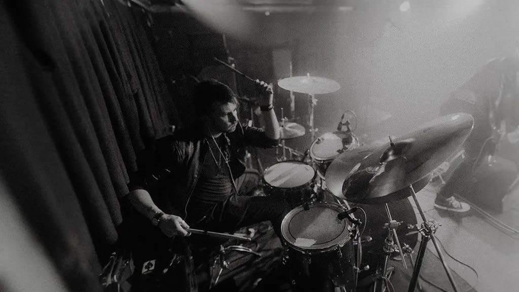 Black and white picture of professional drummer playing acoustic drum kit live on stage