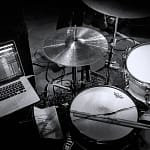 Drum kit set up on stage with Ableton Live on macbook pro black and white greyscale